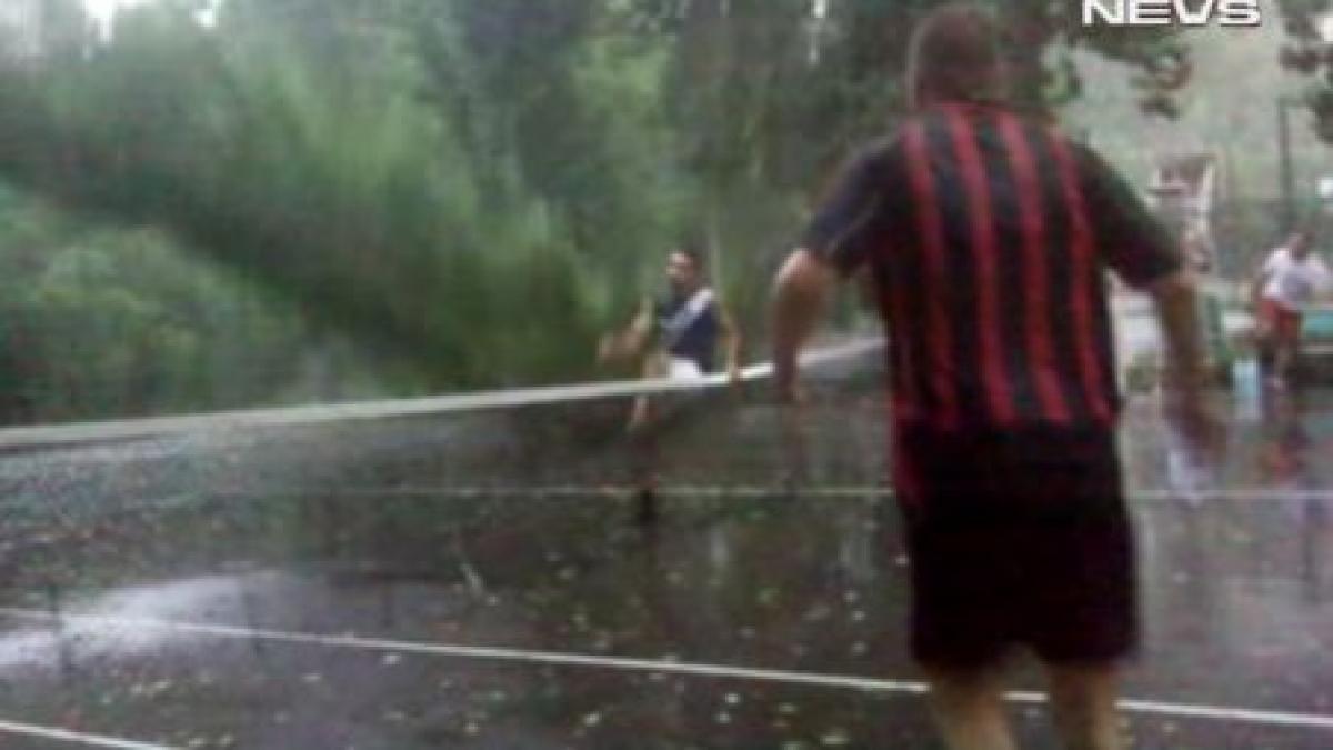 copac doborat de furtuna pe teren in timp ce cativa tineri jucau tenis video