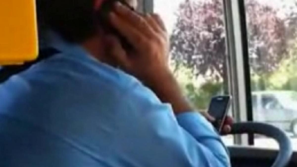 un sofer de autobuz conduce vorbind la un telefon si configurand e mailul pe un altul