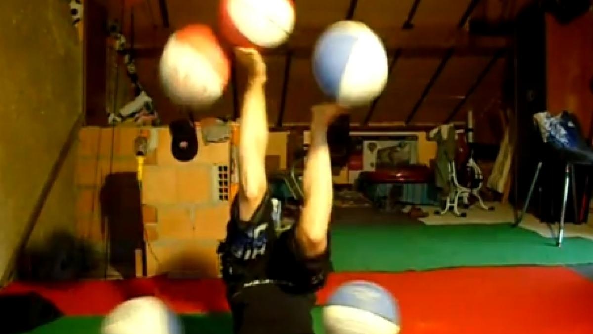 indemanare impresionanta o acrobata jongleaza cu cinci mingii de baschet cu capul in jos