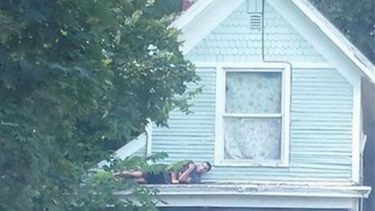 fotografia asta are milioane de vizualizari ce cauta acest barbat cocotat pe acoperisul casei sale