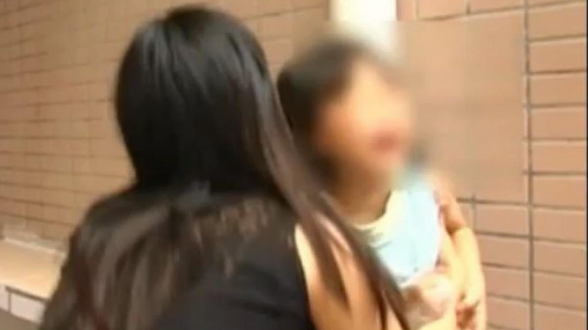 un caine turbat incearca sa smulga o fetita din bratele mamei sale