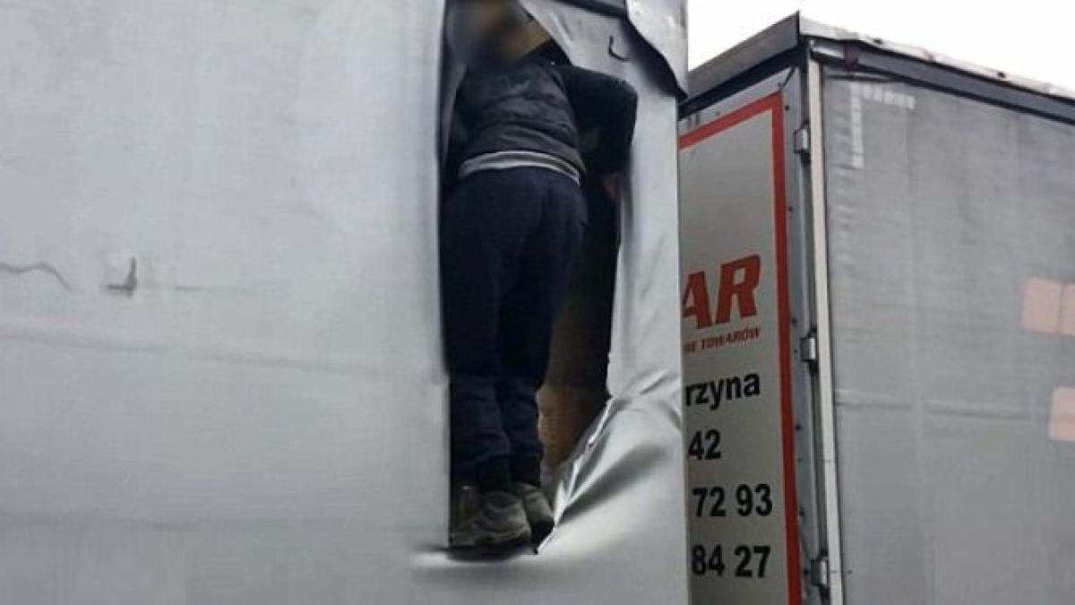 momentul in care un imigrant taie prelata camionului in care se furisase si sare in plin trafic