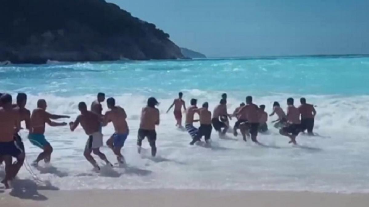 zeci de oameni au facut un lant uman pentru a salva un tata si pe fiul lui din valurile agitate cei