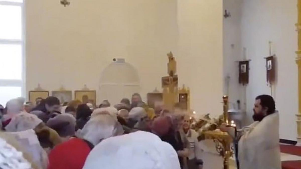 credinciosi stropiti cu furtunul de preot