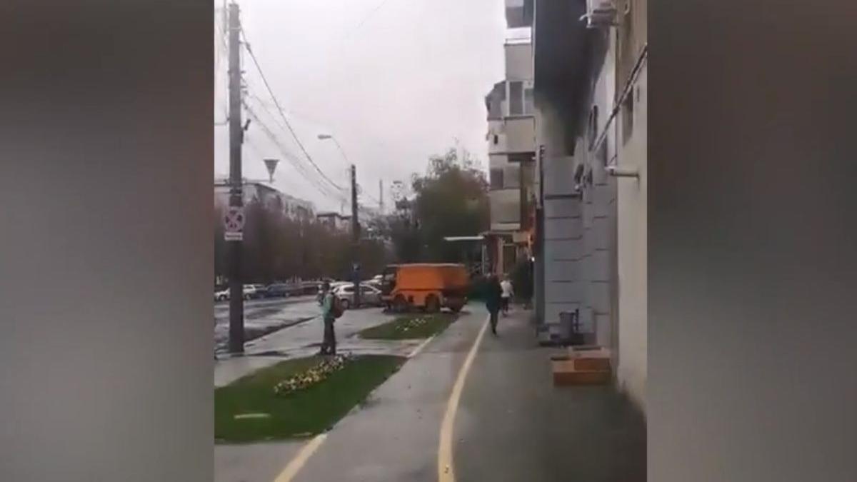 barbat spala asfaltul pe ploaie