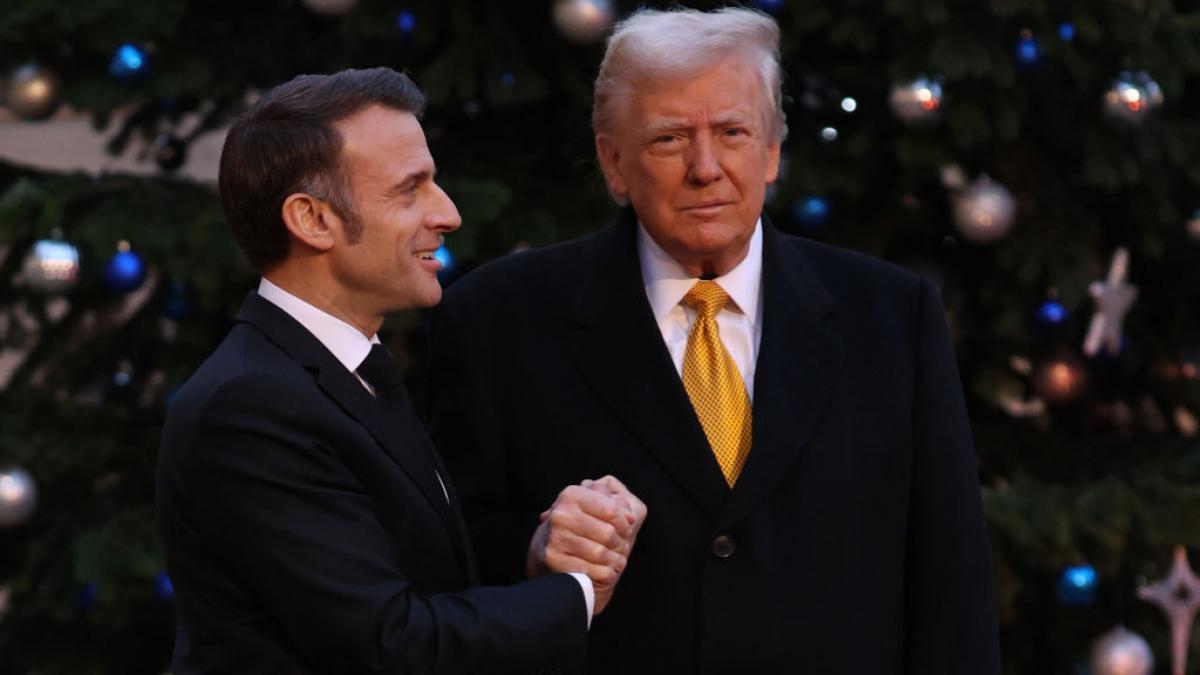 Macron îl privește pe Donald Trump în timp ce îi strânge mâna.