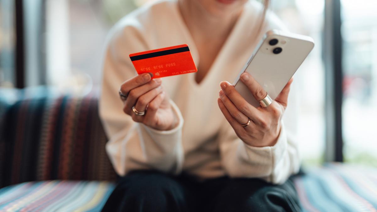 femeie cu cardul bancar si telefonul in mana