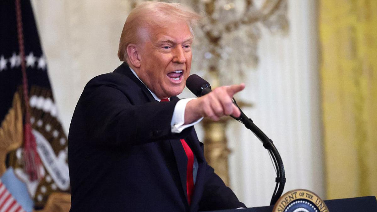 Donald Trump cu un microfon în față arată cu degetul