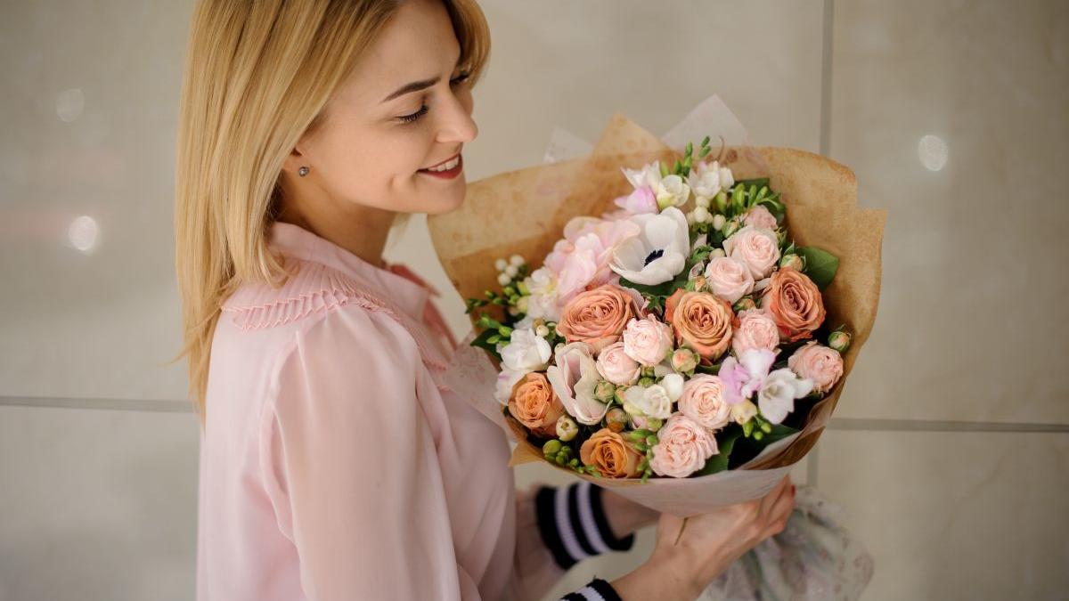 femeie care tine un buchet de flori in mana