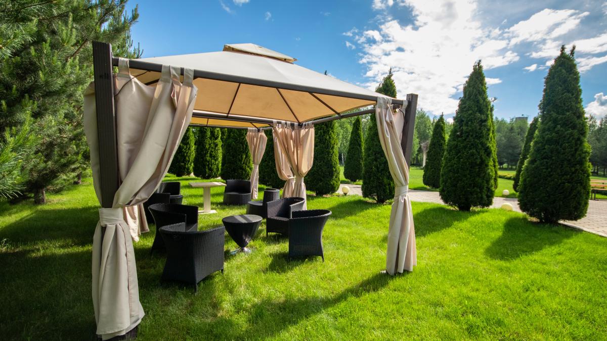 white-canvas-gazebo-with-plastic-garden-furniture-summer-green-lawn