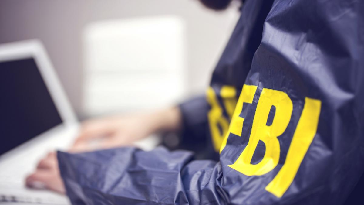 barbat in uniforma fbi in fata unui calculator