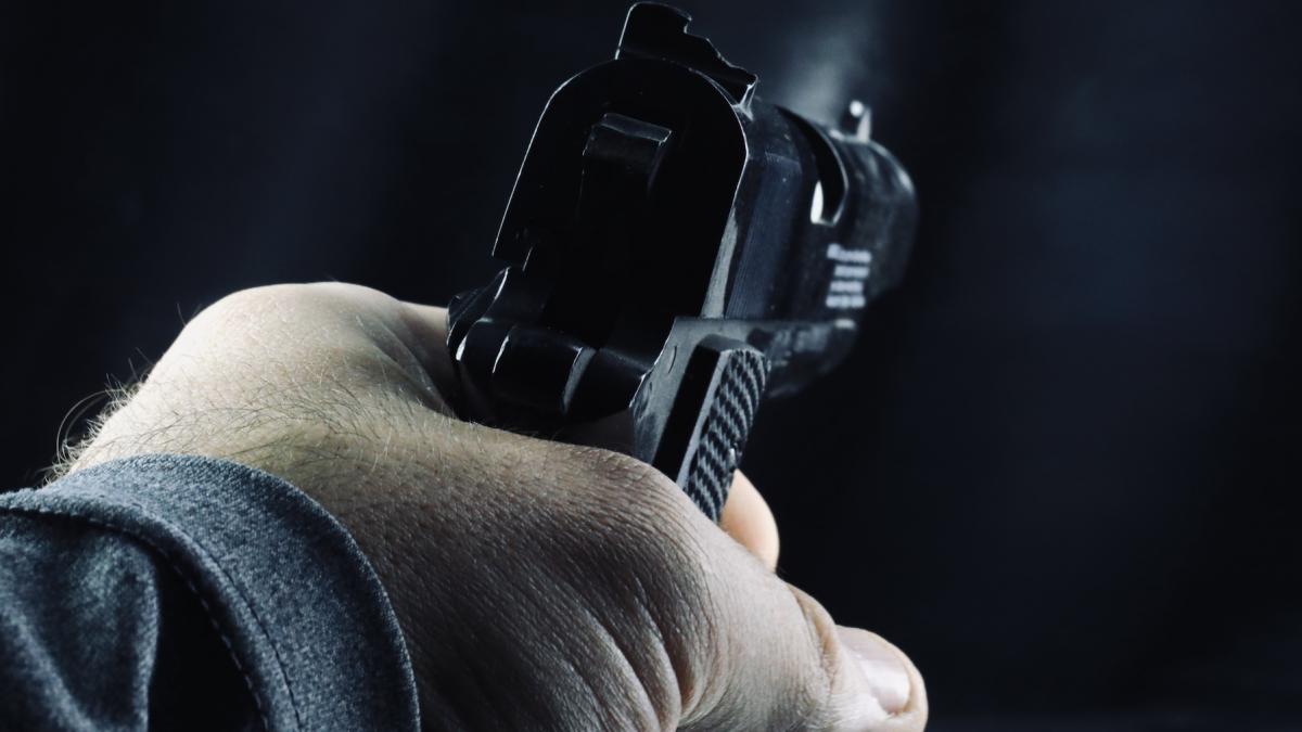 barbat care tine un pistol in mana