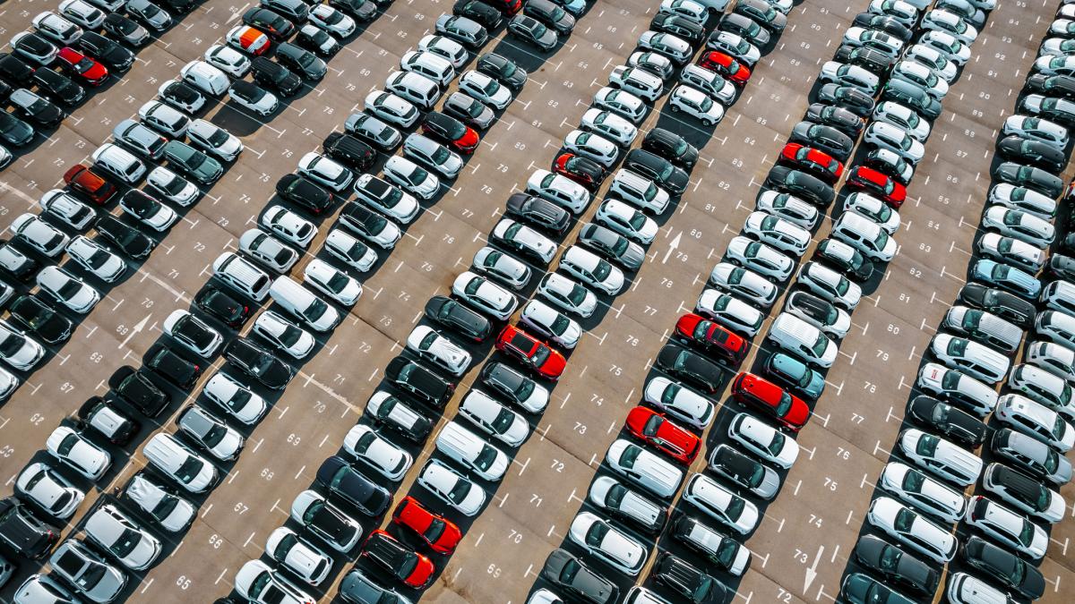 Mai multe masini albe negre si rosii aflate intr-o parcare imensa
