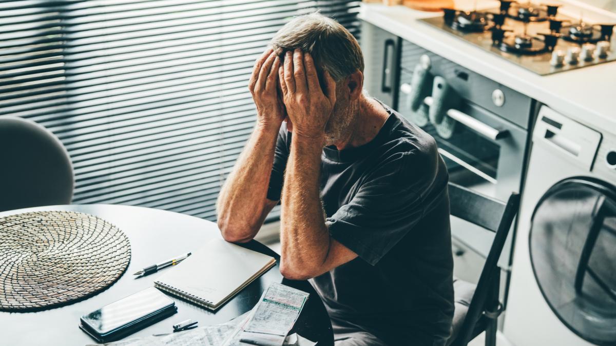 bărbat la masă cu mâinile pe față