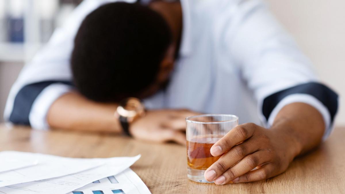 persoana care are in mana un pahar plin cu alcool