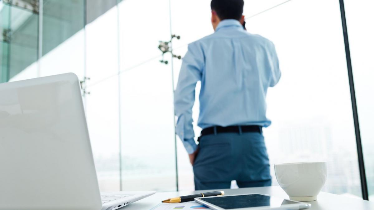 barbat la birou care sta cu spatele
