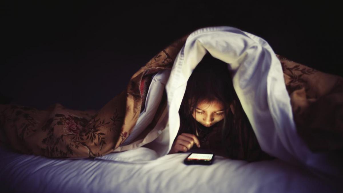 copil sub plapuma se uita in telefon