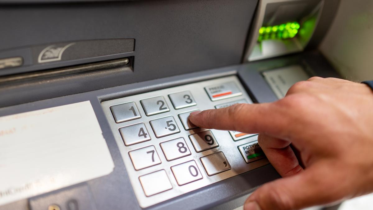 un barbat tasteaza codul PIN la un bancomat