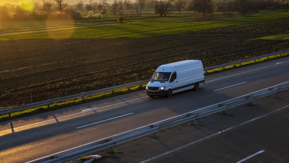 furgoneta condusa pe un drum care traverseaza o zona agricola