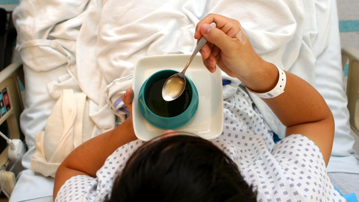 barbat care sta pe patul de spital si mananca supa