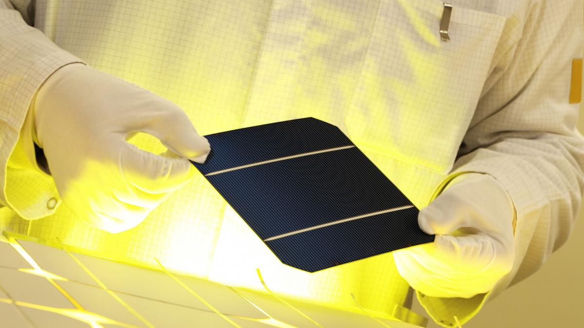 cercetator care lucreaza in laborator cu o bucata de panou solar