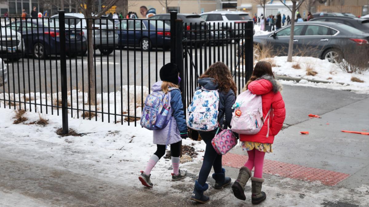 trei copii ies pe poarta scolii