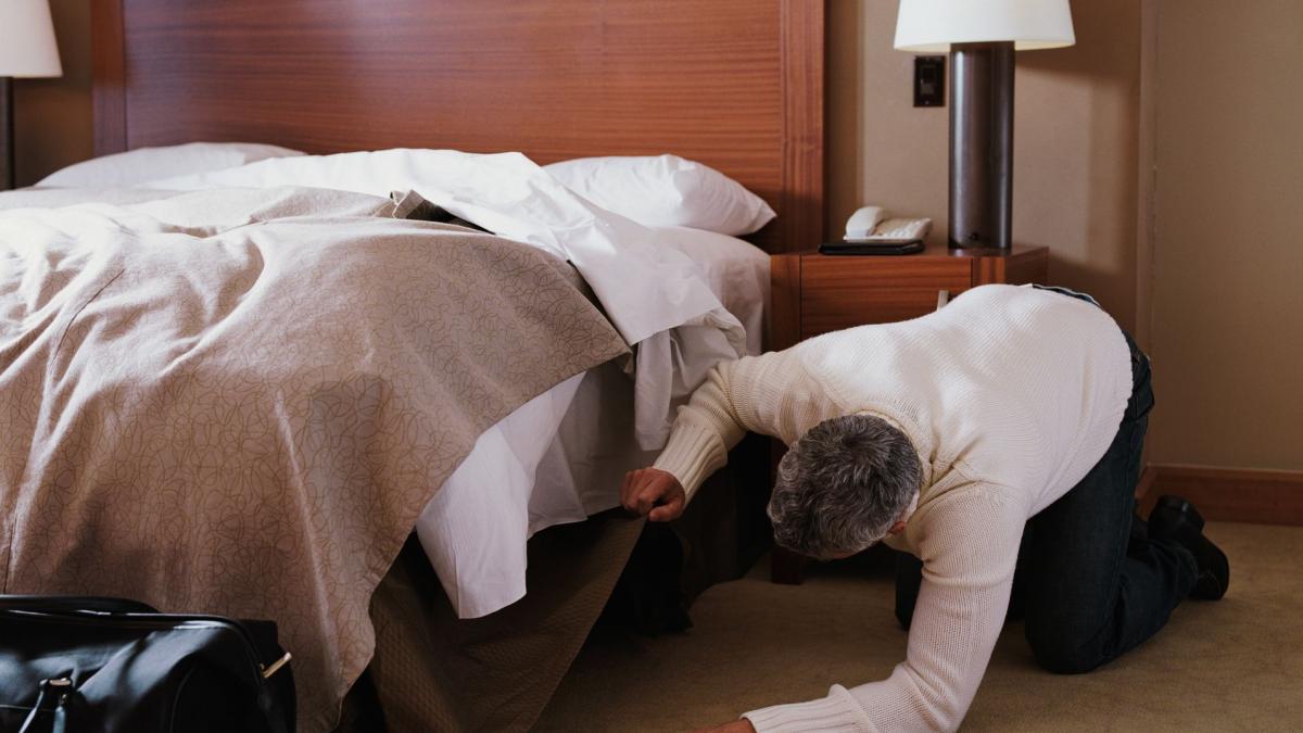 un barbat se uita sub pat