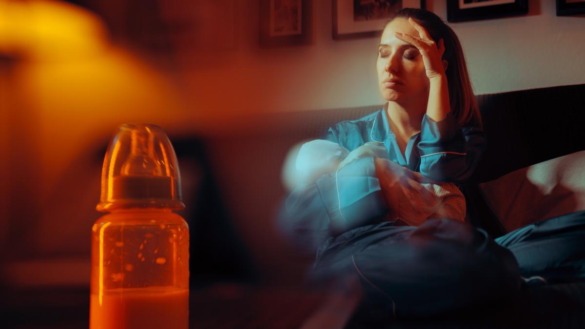 poza in care apare o mama trista care are un copil in brate, iar in prim-plan o sticla cu lapte