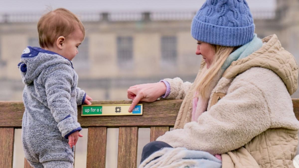 O mama si un bebelus stau pe o banca