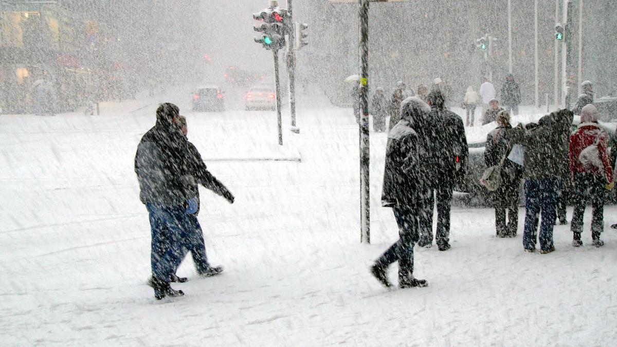 poza facuta intr-o zi in care ninge abundent si sunt oameni pe o strada