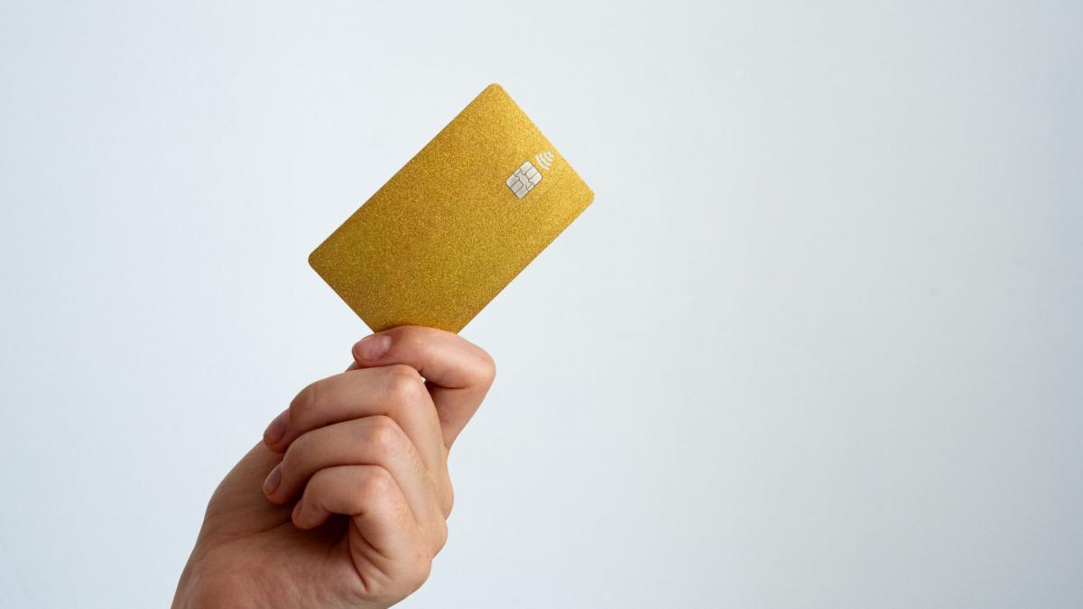 o mana de femeie care tine un card auriu cu chip