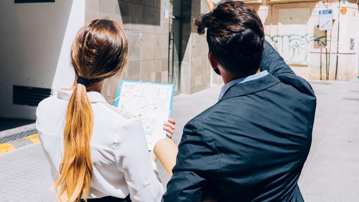 femeie si barbat cu spatele uitandu-se la o cladire