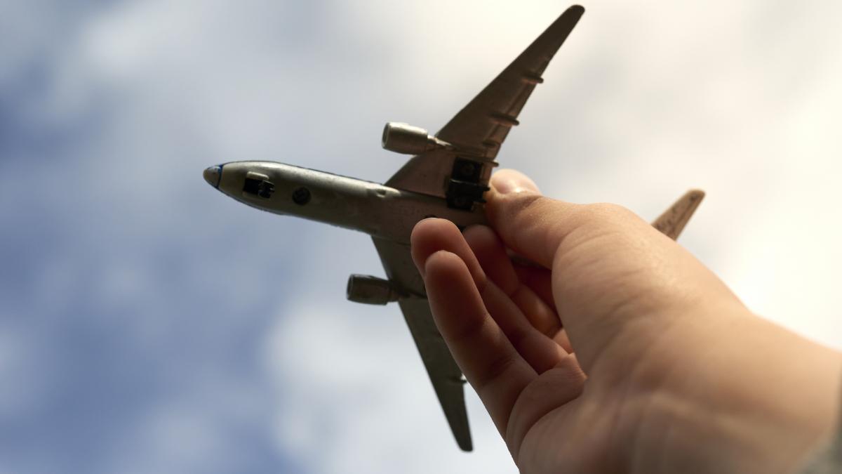 Un copil tine in mana o macheta de avion indreptata catre cer