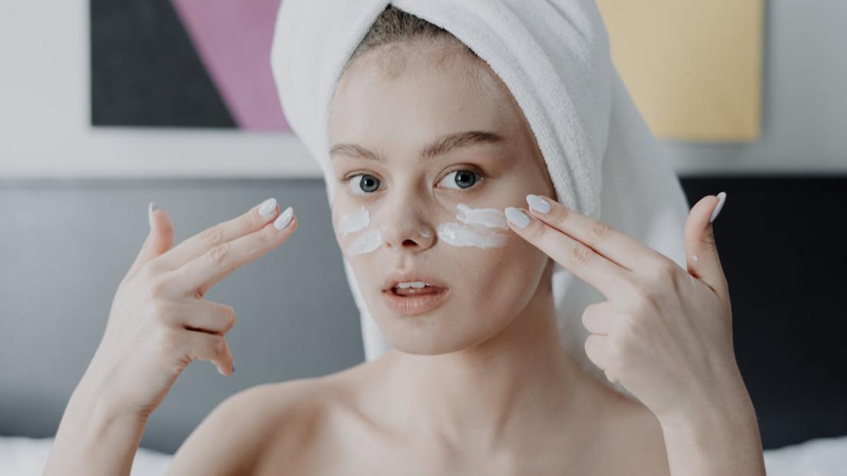 femeie care se da cu crema pe fata
