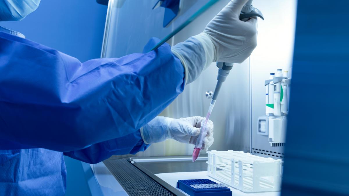 un om de stiinta in laborator cu eprubete si alte instrumente in maini