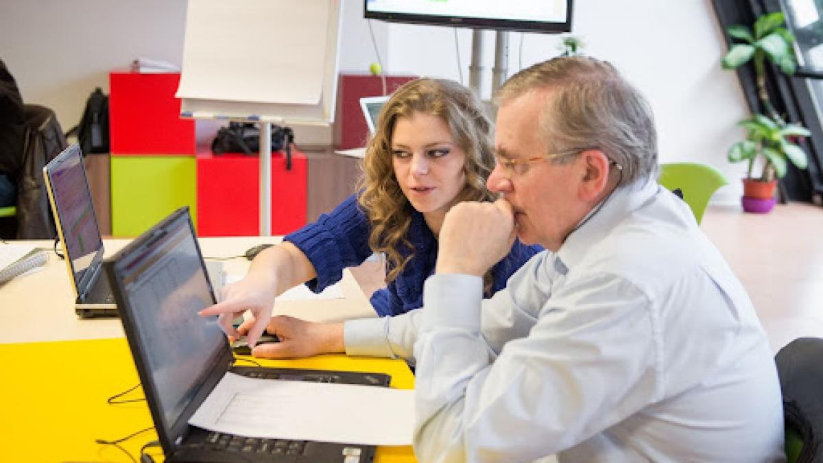 doua persoane uitandu-se pe un laptop