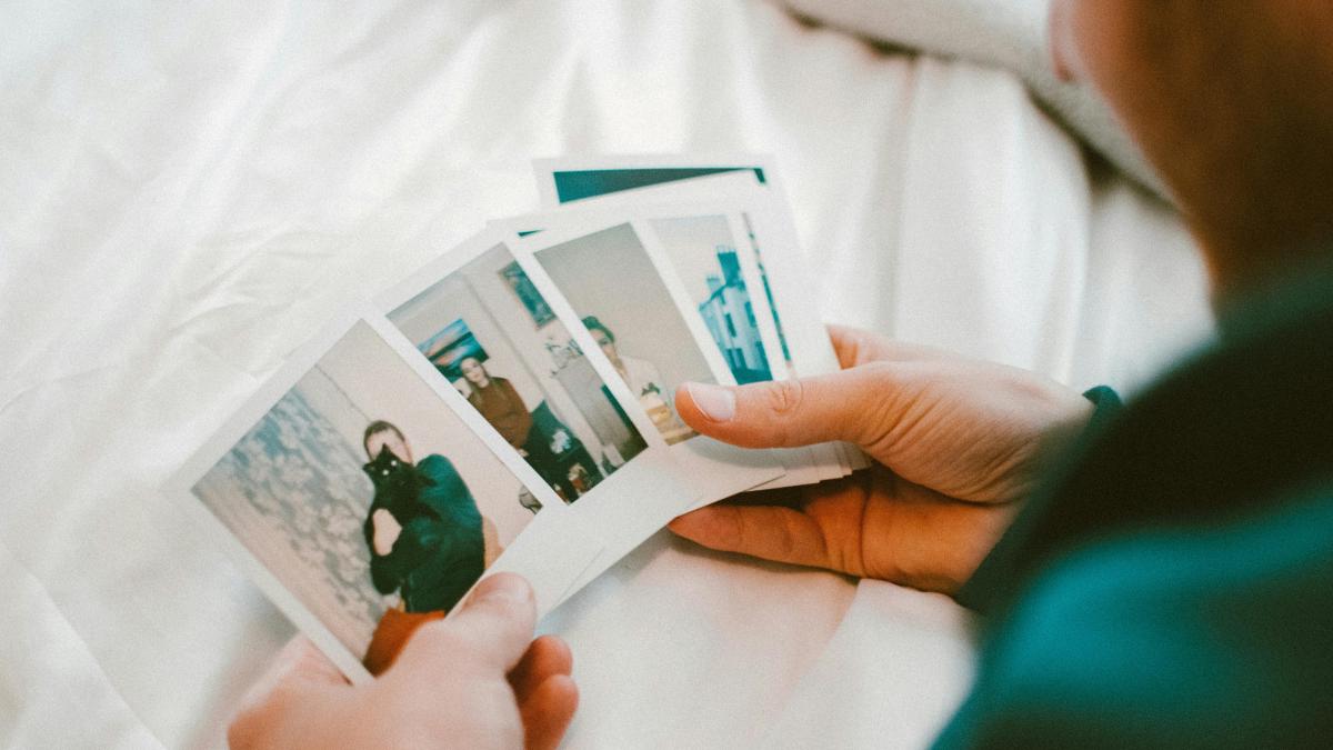 persoana care tine in mana cateva fotografii