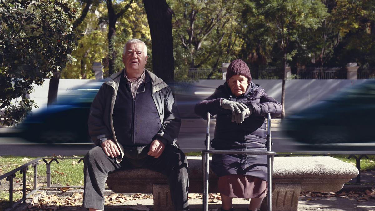 doua persoane in vârsta stând pe bancă