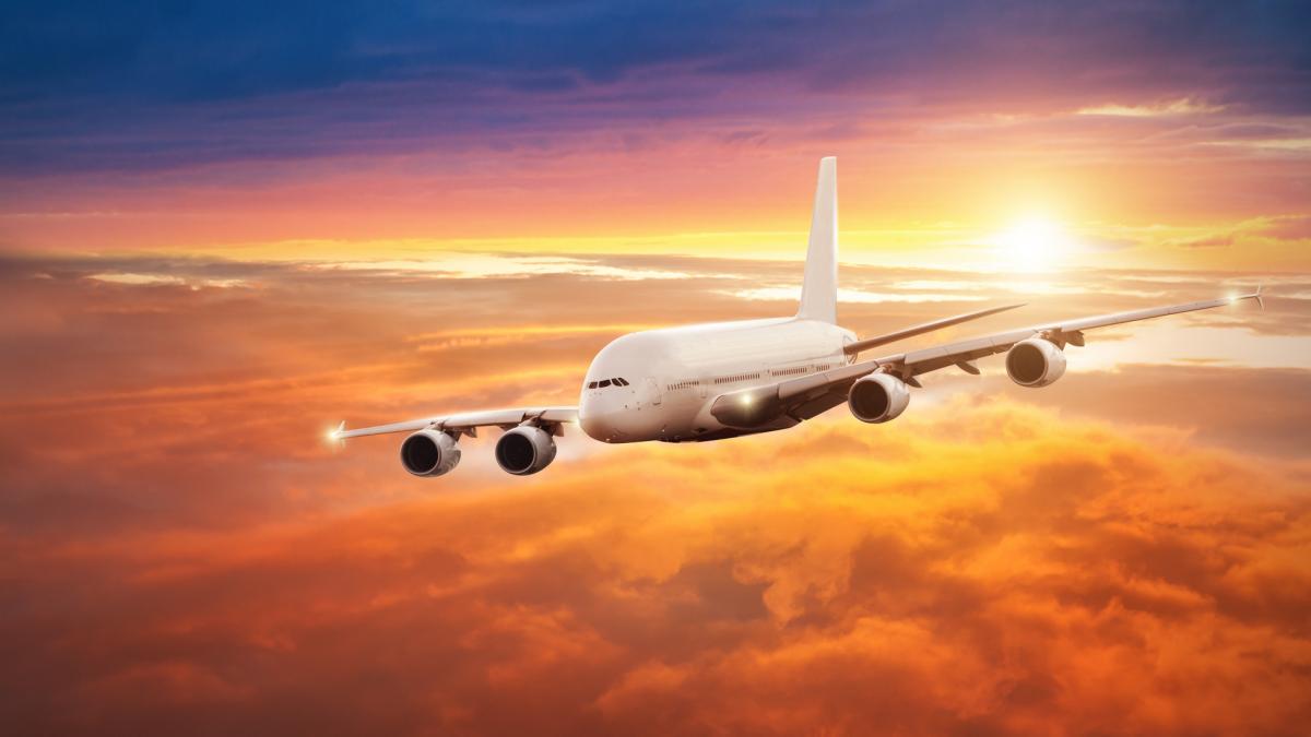 poza in care apare un avion de linie, in aer, în timpul unui apus