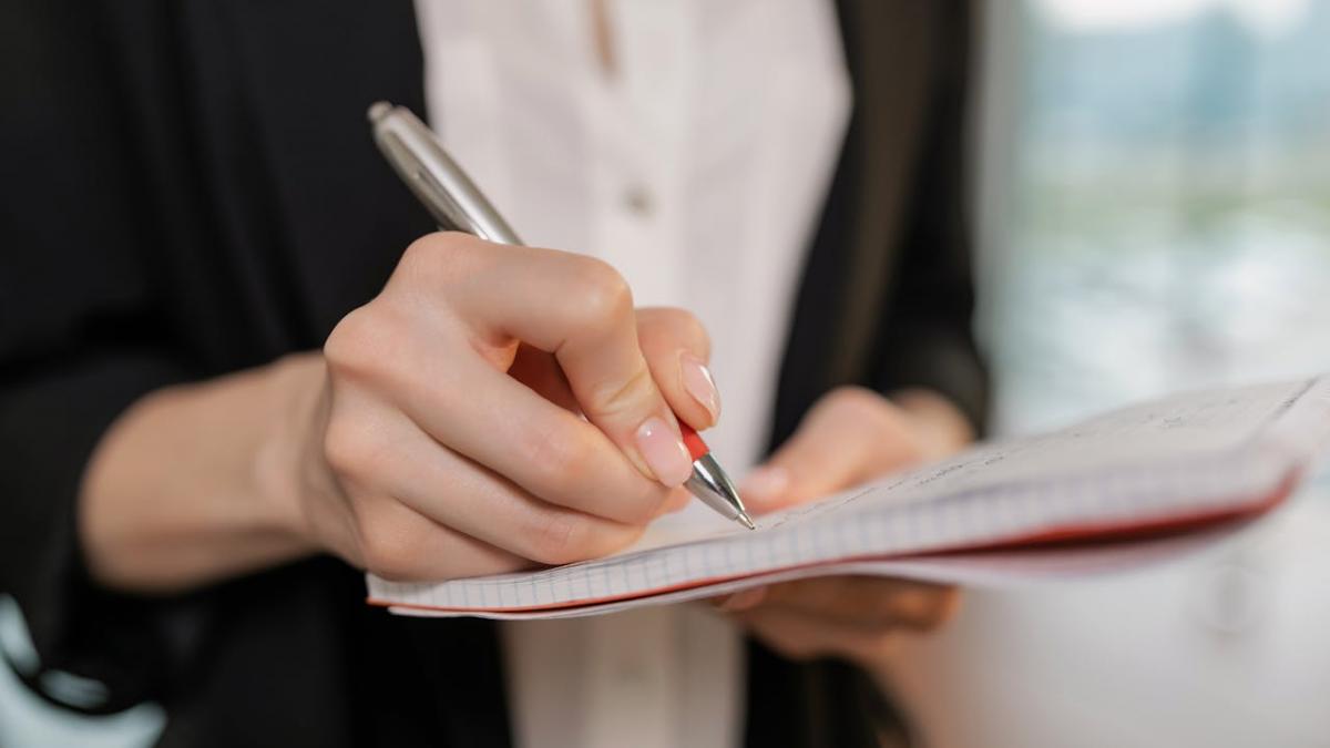 femeie scriind cu pixul intr-o agenda