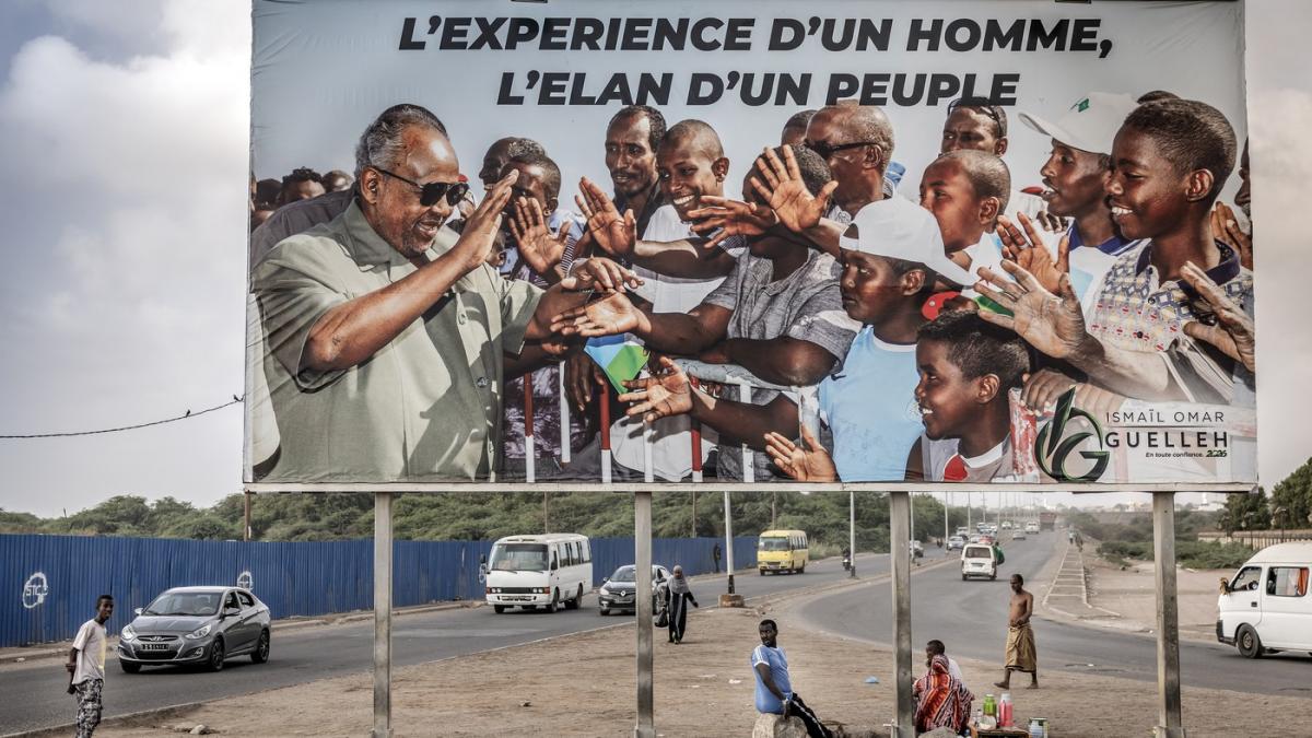 imagine cu o strada din Djibouti, cu un panou electoral cu presedintele Ismail Omar Guelleh sub care stau cativa copii