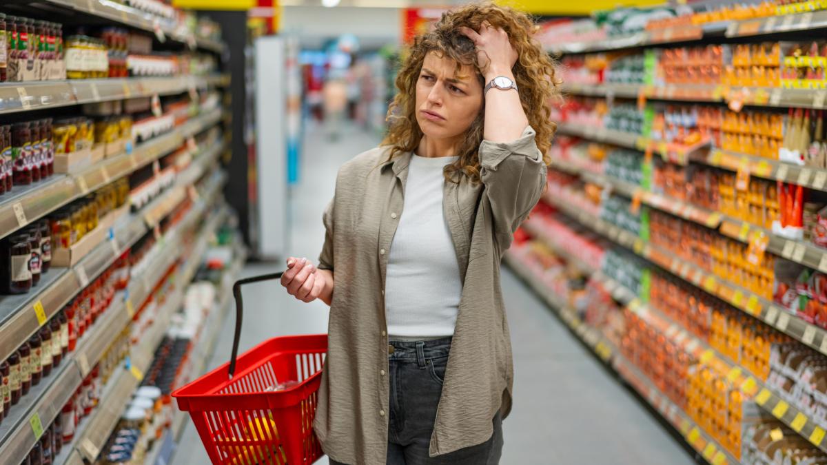 poza in care apare o femeie trista, ingrijorata printre rafturile unui supermarket