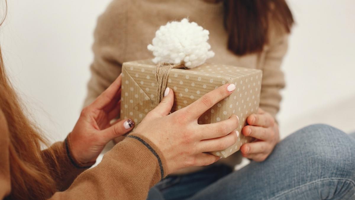 o femeie ii ofera un cadou unei alte femei