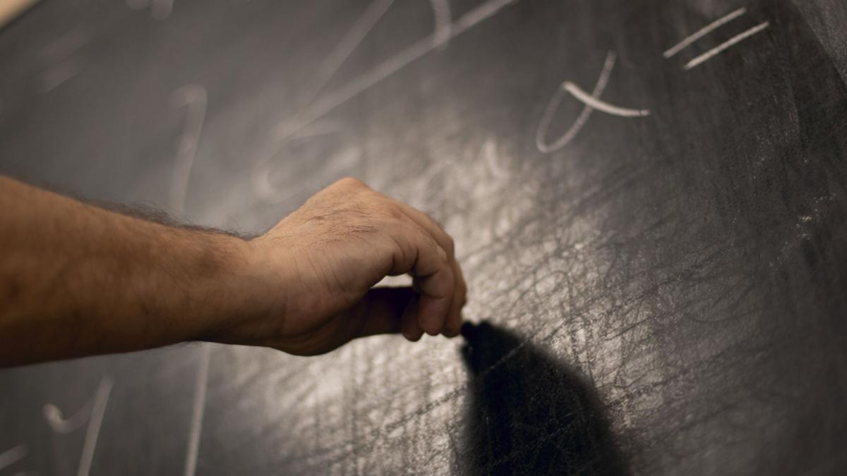 barbat care scrie pe tabla operatii matematice