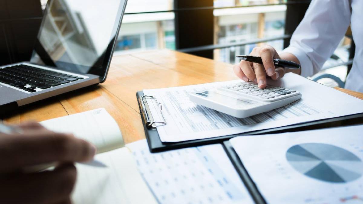 femeie si barbat care completeaza documente si fac calcule pe calculator