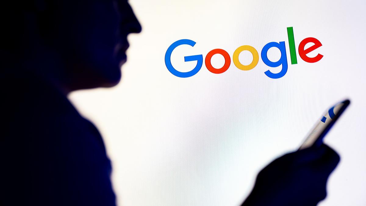 silueta persoana cu telefonul in mana cu logo google pe fundal