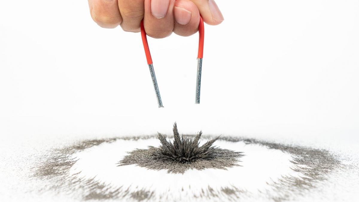 o mana care tine un magnet care atrage particule de metal
