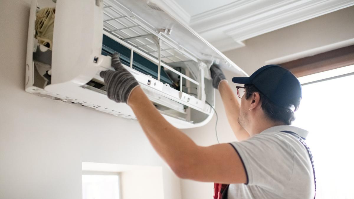 barbat care monteaza un aparat de aer conditionat