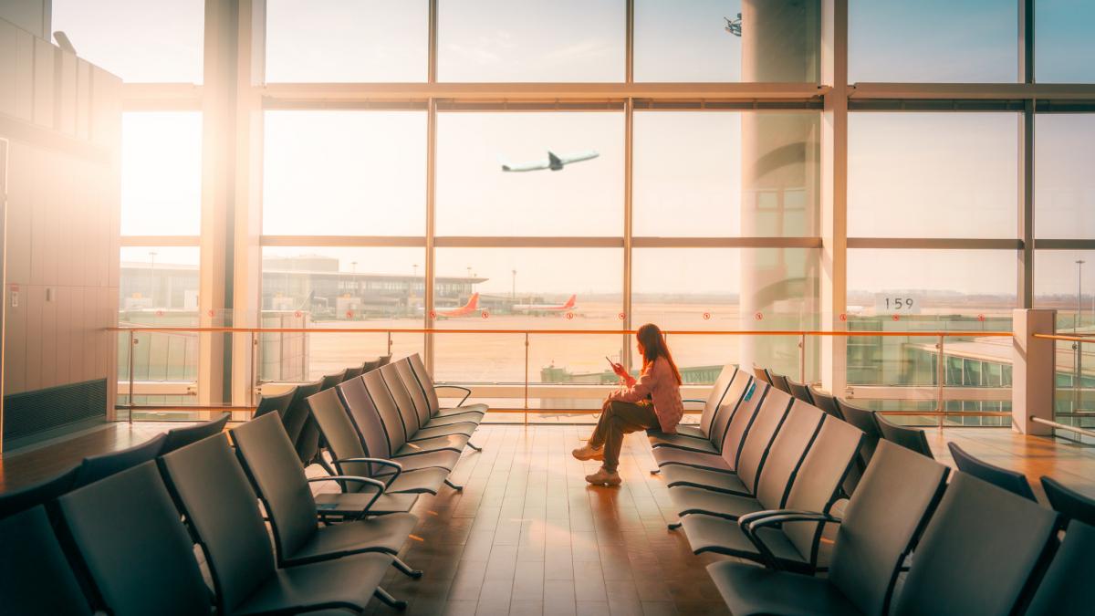 o tanara intr-un aeroport, se vede si un avion