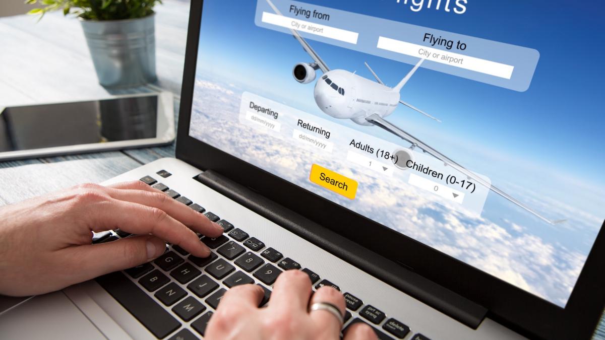 persoana care cauta bilete de avion pe laptop
